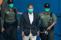 FILE- Hong Kong media tycoon Jimmy Lai is escorted by Correctional Services officers to get on a prison van before appearing in a court in Hong Kong, Dec. 12, 2020. (AP Photo/Kin Cheung, File)