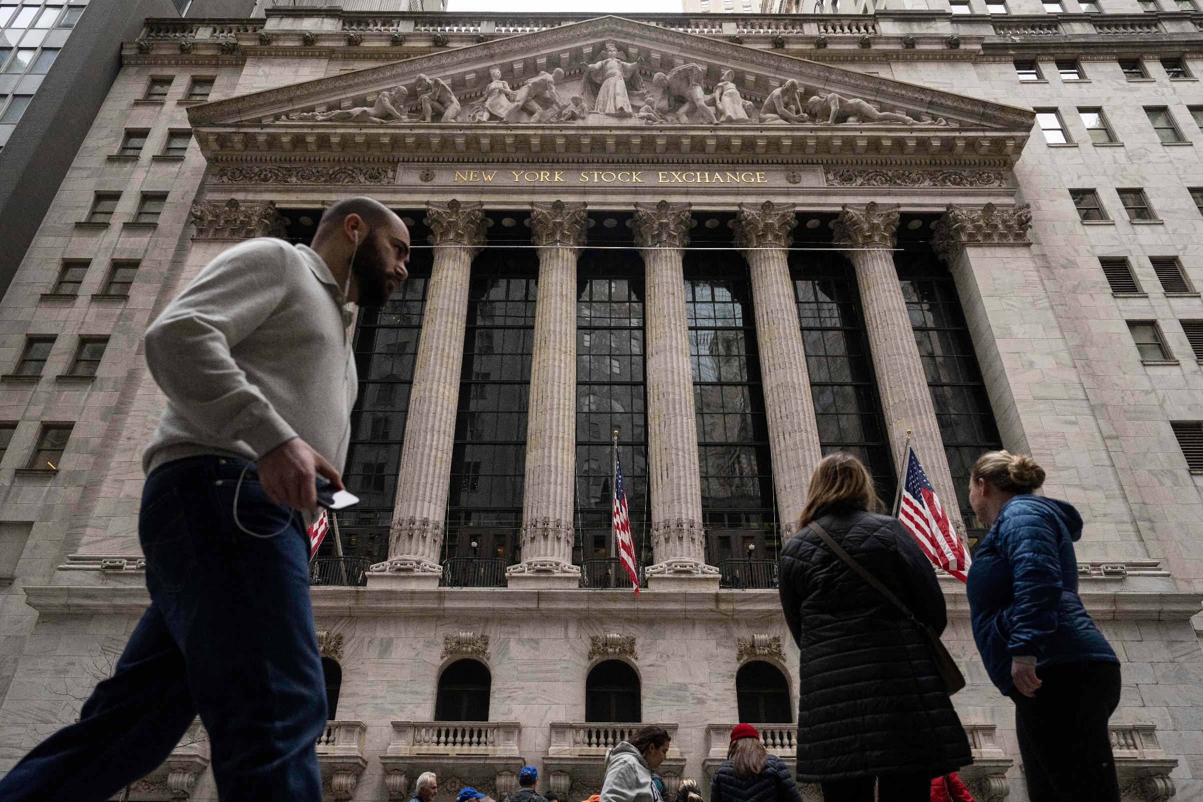 People walk past the New York Stock Exchange, Friday, March 27, 2026, in New York. (AP Photo/Yuki Iwamura)