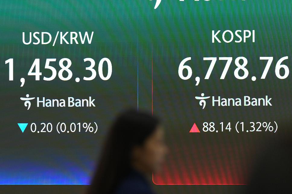 A dealer walks past near the screens showing the Korea Composite Stock Price Index (KOSPI) and the foreign exchange rate between U.S. dollar and South Korean won at a dealing room of Hana Bank in Seoul, South Korea, Monday, July 27, 2026. (AP Photo/Lee Jin-man)