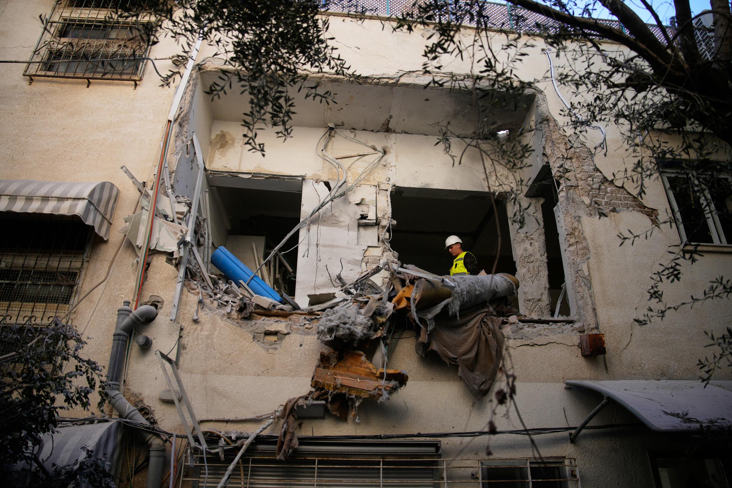 Israeli security forces inspect a damaged apartment building struck by an Iranian missile in Tel Aviv, Israel, Sunday, March 8, 2026. (AP Photo/Ohad Zwigenberg)