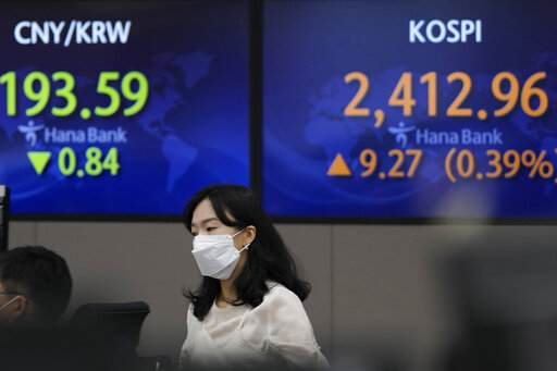 A currency trader walks near the screens showing the Korea Composite Stock Price Index (KOSPI), right, and the foreign exchange rate at a foreign exchange dealing room in Seoul, South Korea, Wednesday, July 27, 2022. Asian stock markets followed Wall Street lower Wednesday as traders prepared for a possible sharp interest rate hike from the Federal Reserve to cool inflation. (AP Photo/Lee Jin-man)