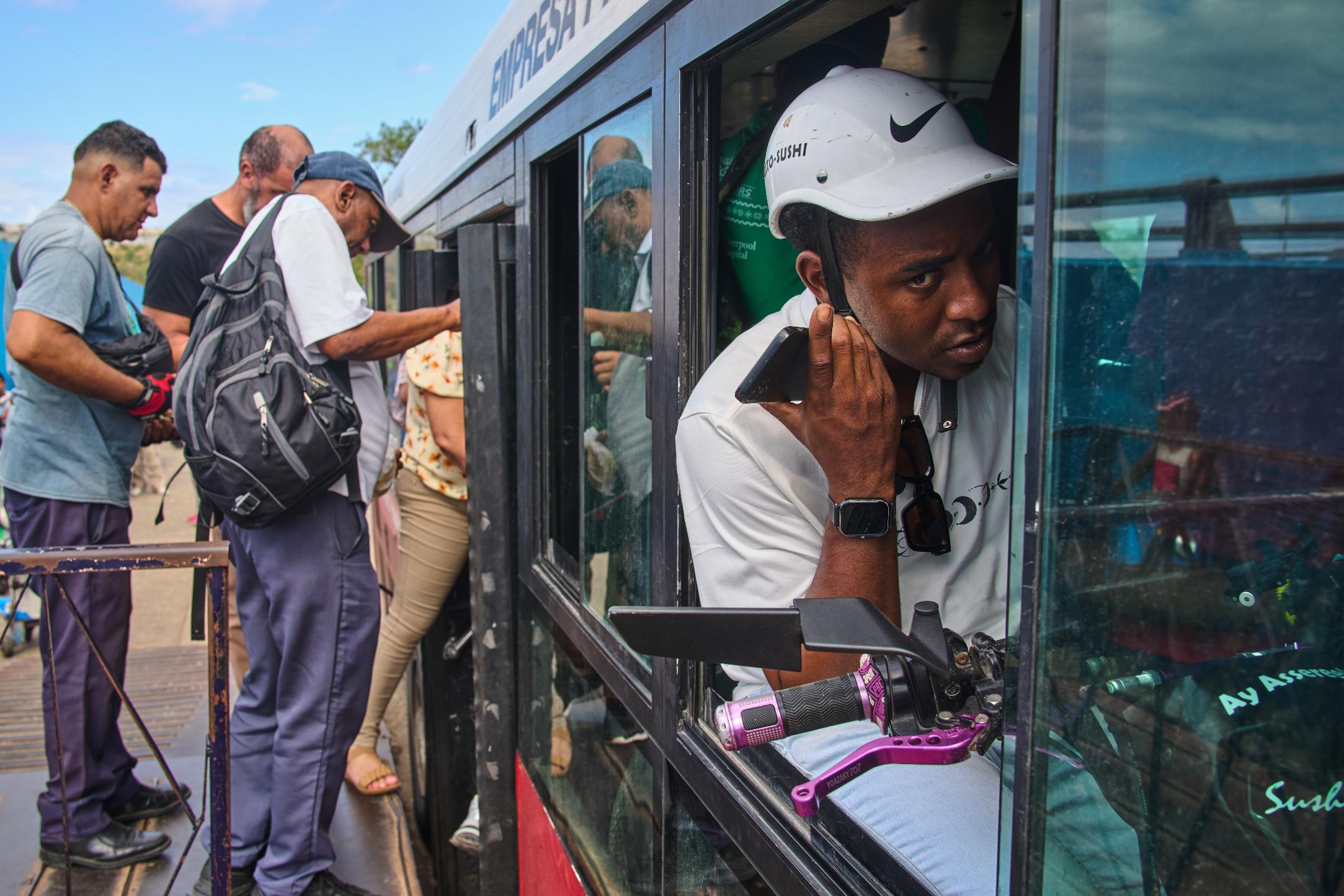 A man speaks on the phone while holding his electric bicycle in a public bus to cross the Bay Tunnel in Havana, Wednesday, April 8, 2026. (AP Photo/Ramon Espinosa)