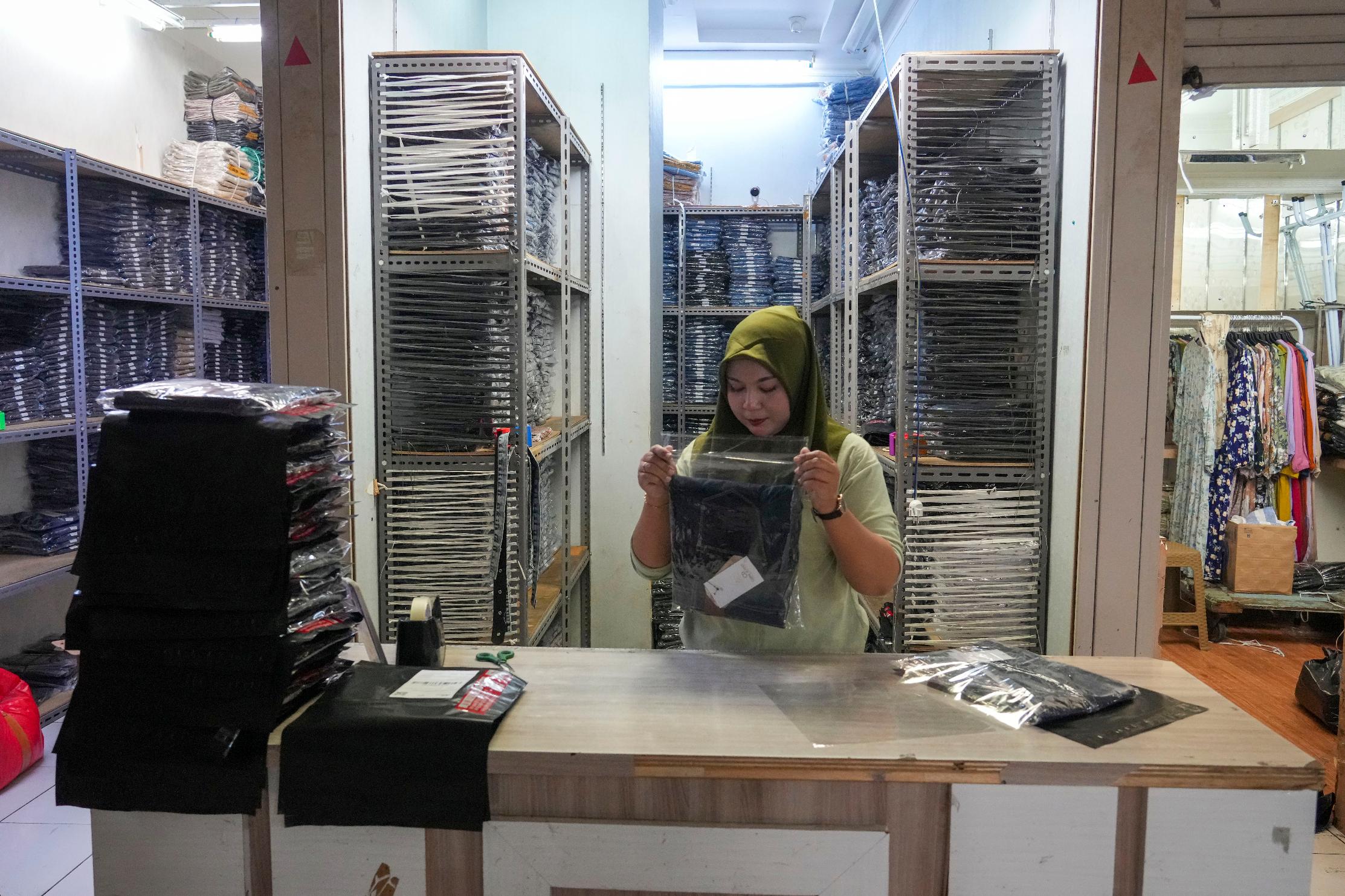 A seller wraps merchandise to send to her customer who she's dealing, using live streaming at a store in the Tanah Abang textile market in Jakarta, Indonesia, Wednesday, Oct. 4, 2023. TikTok said it will halt its online-retail operation in Indonesia on Wednesday to comply with the country's decision to ban e-commerce transactions on social media platforms, a big blow to the video platform's fastest-growing market. (AP Photo/Tatan Syuflana)