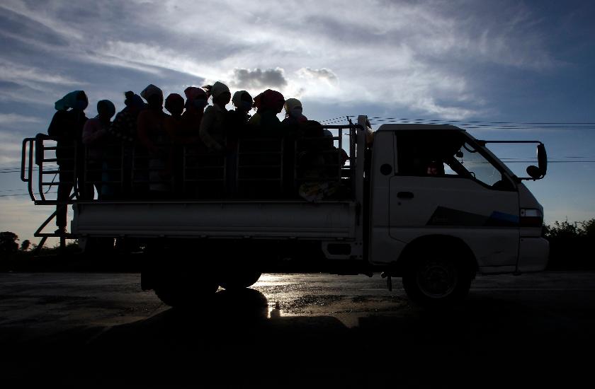 FILE -In this Dec. 3, 2018 photo, garment factory workers ride a truck as they go home after a day's work at outside Phnom Penh, Cambodia. (AP Photo/Heng Sinith, File)