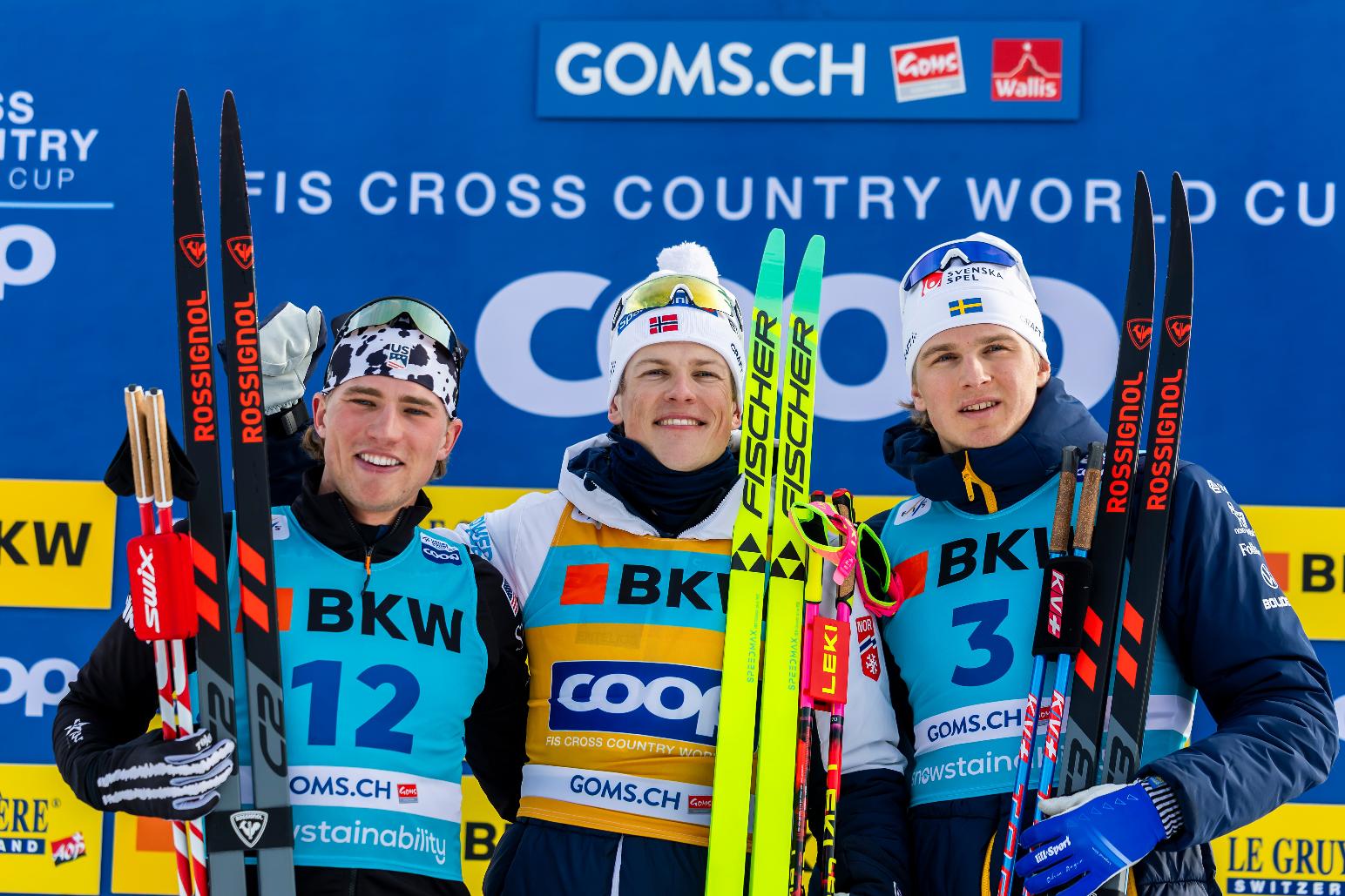 Winner Johannes Hoesflot Klaebo of Norway, centre, second placed Gus Schumacher of United States, left, and Edvin Anger of Sweden, right, celebrate on the podium after the men's sprint final classic skiing race, during the FIS Cross-Country World Cup at the Nordic Center Goms, in Geschinen, Switzerland, Saturday, Jan. 24, 2026. (Salvatore Di Nolfi/Keystone via AP)