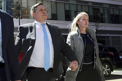 John Wilson, left, arrives at federal court, April 3, 2019, with his wife Leslie to face charges in a nationwide college admissions bribery scandal in Boston. Wilson, a head of a private equity firm and former Staples Inc. executive, was convicted in March 2022 of bribery and fraud charges for trying to pay more than $1.2 million to buy his three children's way into elite universities. Wilson's attorney's appealed the conviction in a filing Monday April 25, 2022, alleging prosecutorial flaws and an unfair trial. (AP Photo/Charles Krupa, File)
