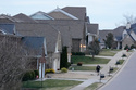 A person walks past single family homes, Tuesday, Feb. 10, 2026, in Nashville, Tenn. (AP Photo/George Walker IV)