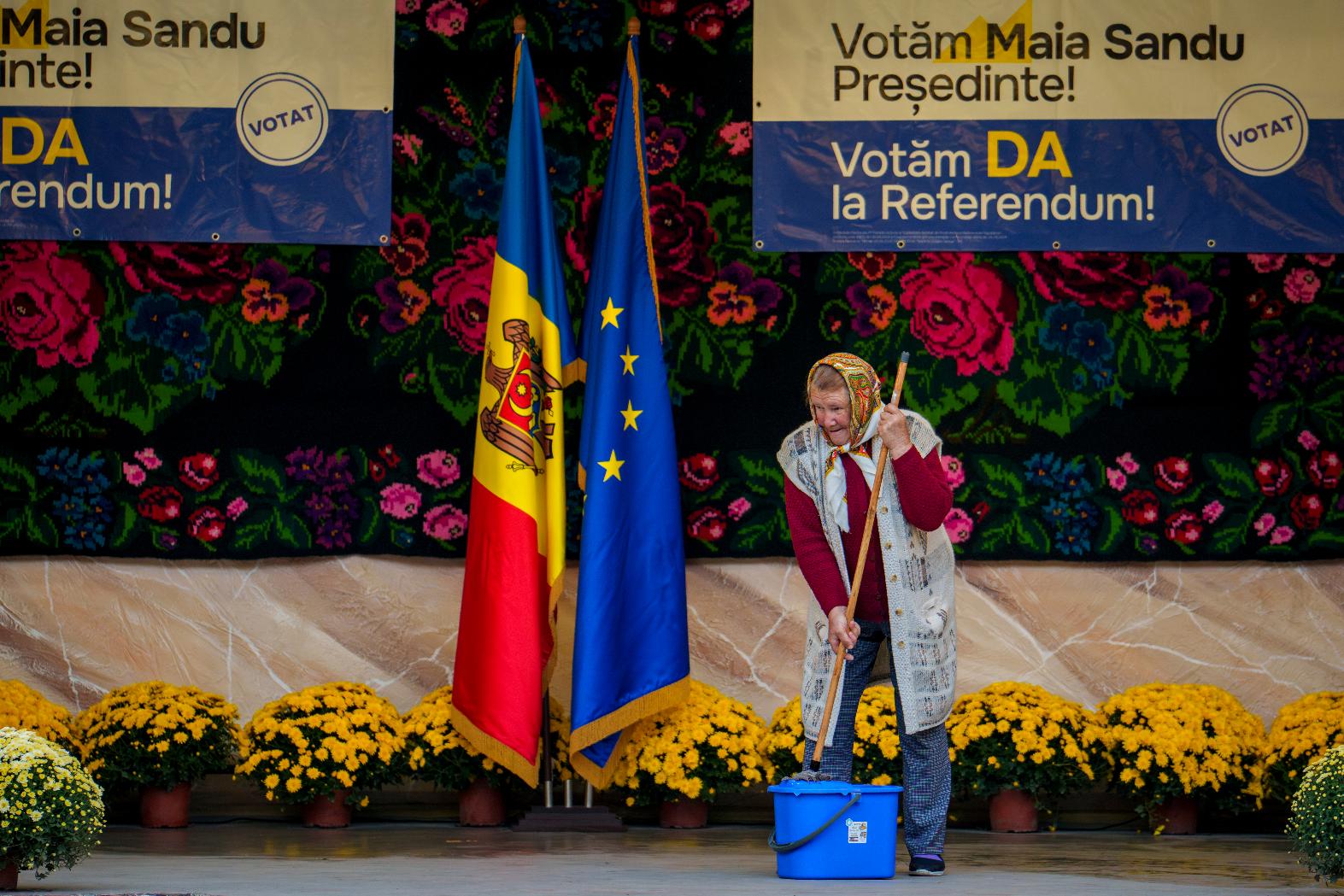 FILE - A woman mops a stage before an electoral rally of Moldova's President Maia Sandu in Magdacesti, Moldova, Oct. 17, 2024. (AP Photo/Vadim Ghirda, File)