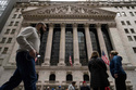 People walk past the New York Stock Exchange, Friday, March 27, 2026, in New York. (AP Photo/Yuki Iwamura)