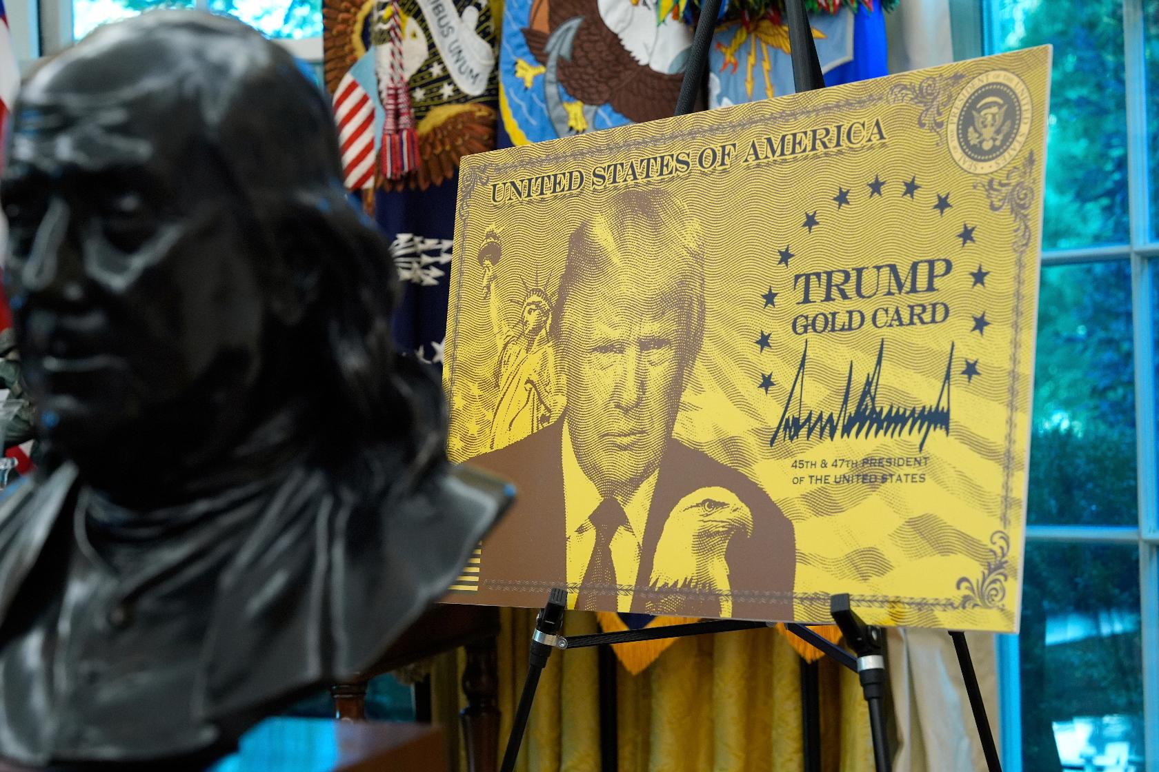 A poster showing the Trump Gold Card is pictured as President Donald Trump speaks in the Oval Office of the White House, Friday, Sept. 19, 2025, in Washington. (AP Photo/Alex Brandon)