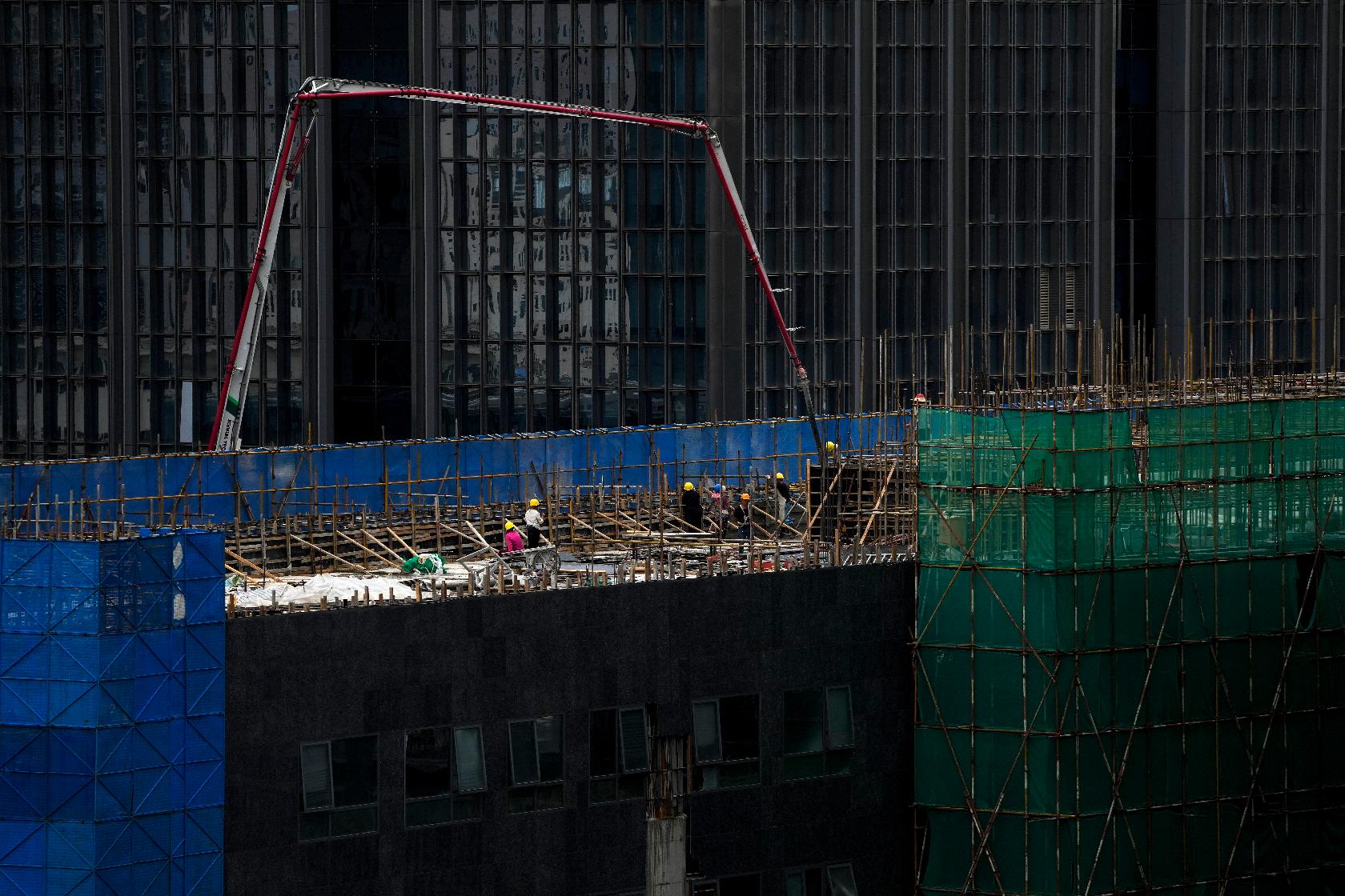 Workers use a machine to pour cement on a reconstruction office building in Beijing on Aug. 6, 2023. China’s government skipped giving an update on a politically sensitive spike in unemployment among young people as official data Tuesday, Aug. 15, showed an economic slump deepened in July. (AP Photo/Andy Wong)