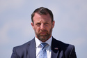 Homeland Security Secretary Markwayne Mullin, listens as President Donald Trump speaks to the press after returning and stepping off Air Force One, Wednesday, May 20, 2026, at Joint Base Andrews, Md. (AP Photo/Jacquelyn Martin)