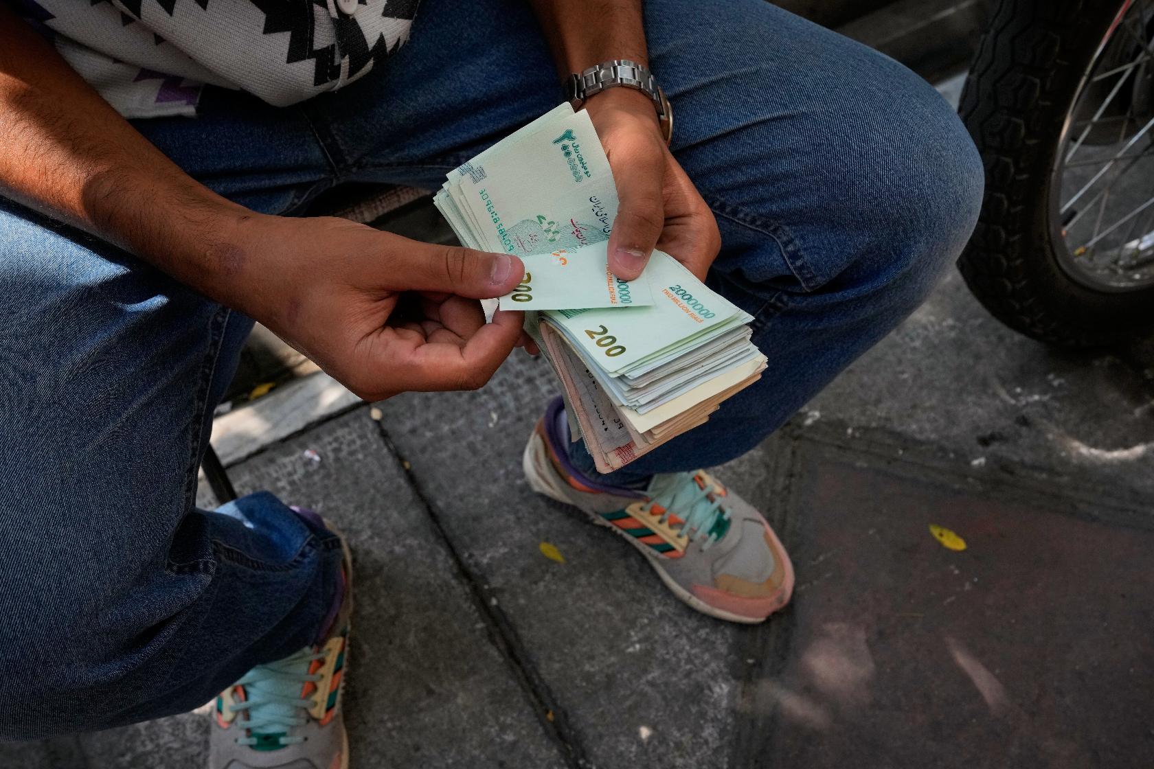 A money exchanger counts Iranian banknotes at Ferdowsi square, Tehran's go-to venue for foreign currency exchange, in downtown Tehran, Iran, Monday, Aug. 24, 2026. AP Photo/Vahid Salemi)
