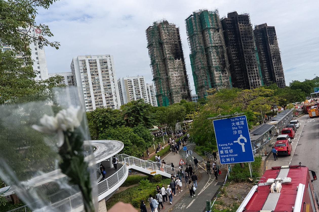 People look at the burned buildings near the site of a deadly Wednesday fire at Wang Fuk Court, a residential estate in the Tai Po district of Hong Kong's New Territories on Monday, Dec. 1, 2025. (AP Photo/Chan Long Hei)