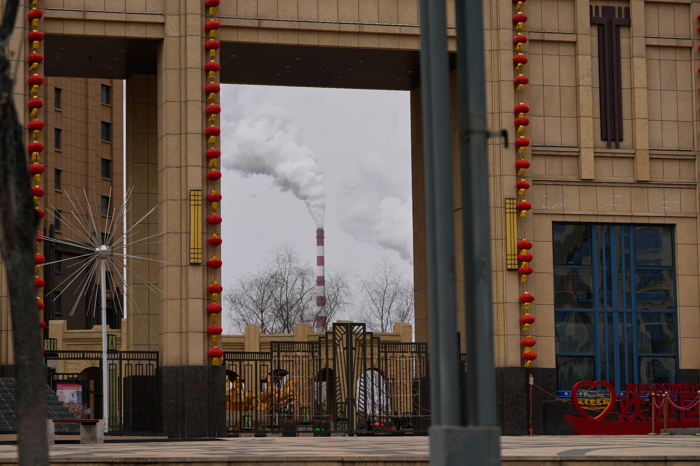 A chimney of a coal-fired power plant is visible near a residential complex in Datong, China, Saturday, March 14, 2026. (AP Photo/Ng Han Guan)