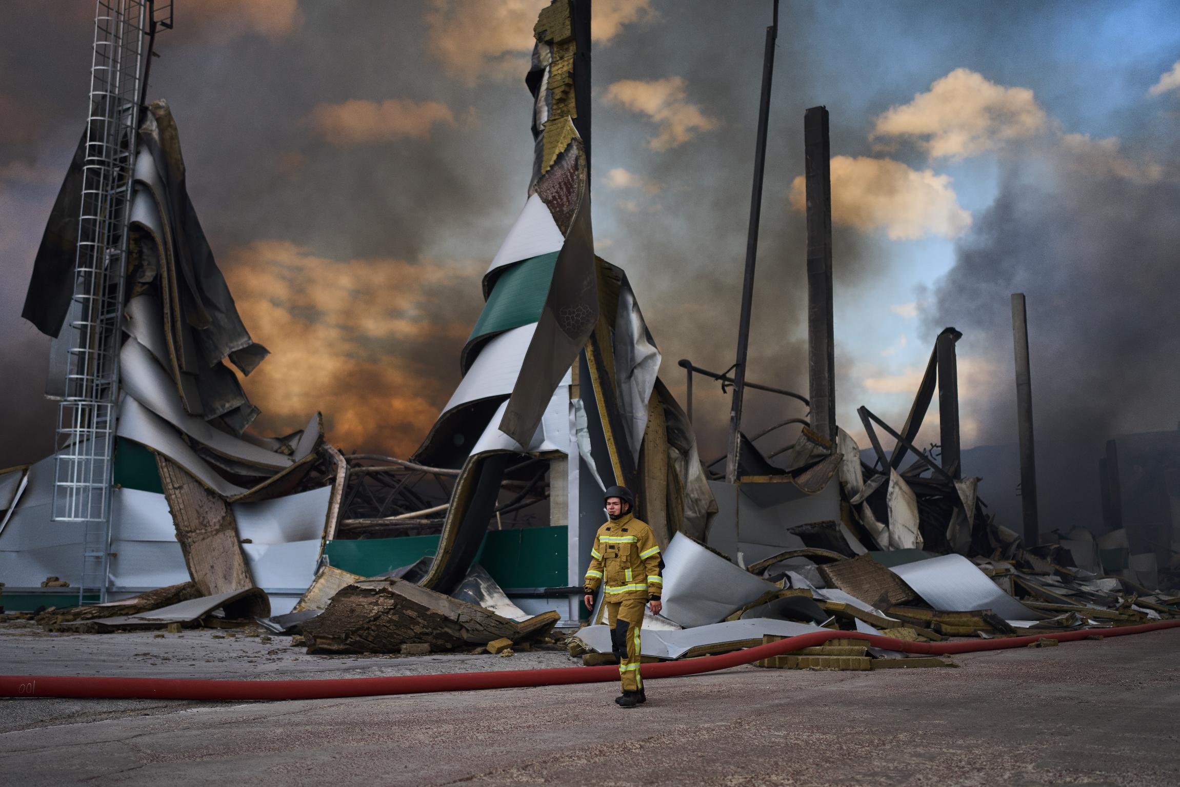 A firefighter walks next to a destroyed warehouse after Russian drone attacks at the outskirt of Kyiv, Ukraine, Thursday, Aug. 27, 2026. (AP Photo/Francisco Seco)