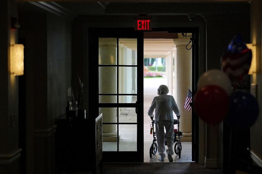 FILE - A woman uses a walker as she exits an assisted living building, July 4, 2025, in Boca Raton, Fla. (AP Photo/Rebecca Blackwell, File)