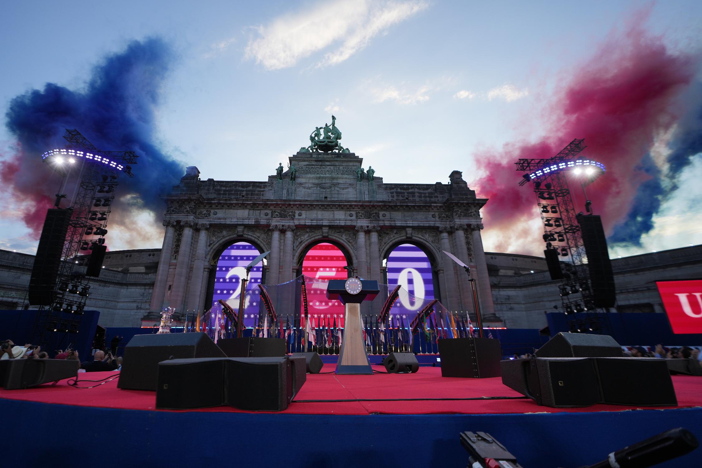 Colored smoke is lit behind the Cinquantenaire Arch to celebrate during the America 250 event in Brussels, Sunday, June 28, 2026. (AP Photo/Virginia Mayo)