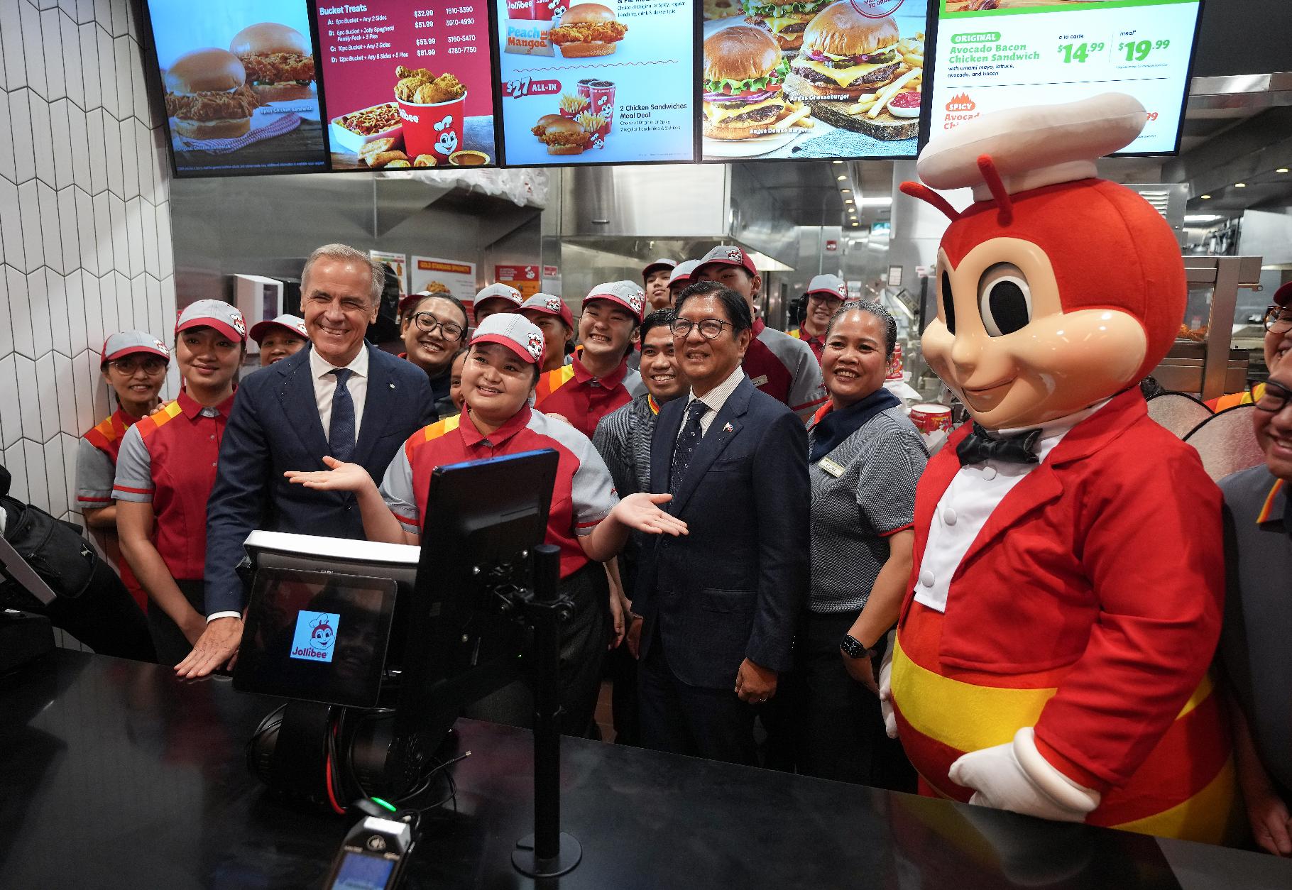 Canada's Prime Minister Mark Carney, left, and Philippines President Ferdinand Marcos Jr., right, pose with employees during a visit to a Jollibee fast food restaurant, in Vancouver, Thursday, July 2, 2026. (Darryl Dyck/The Canadian Press via AP)