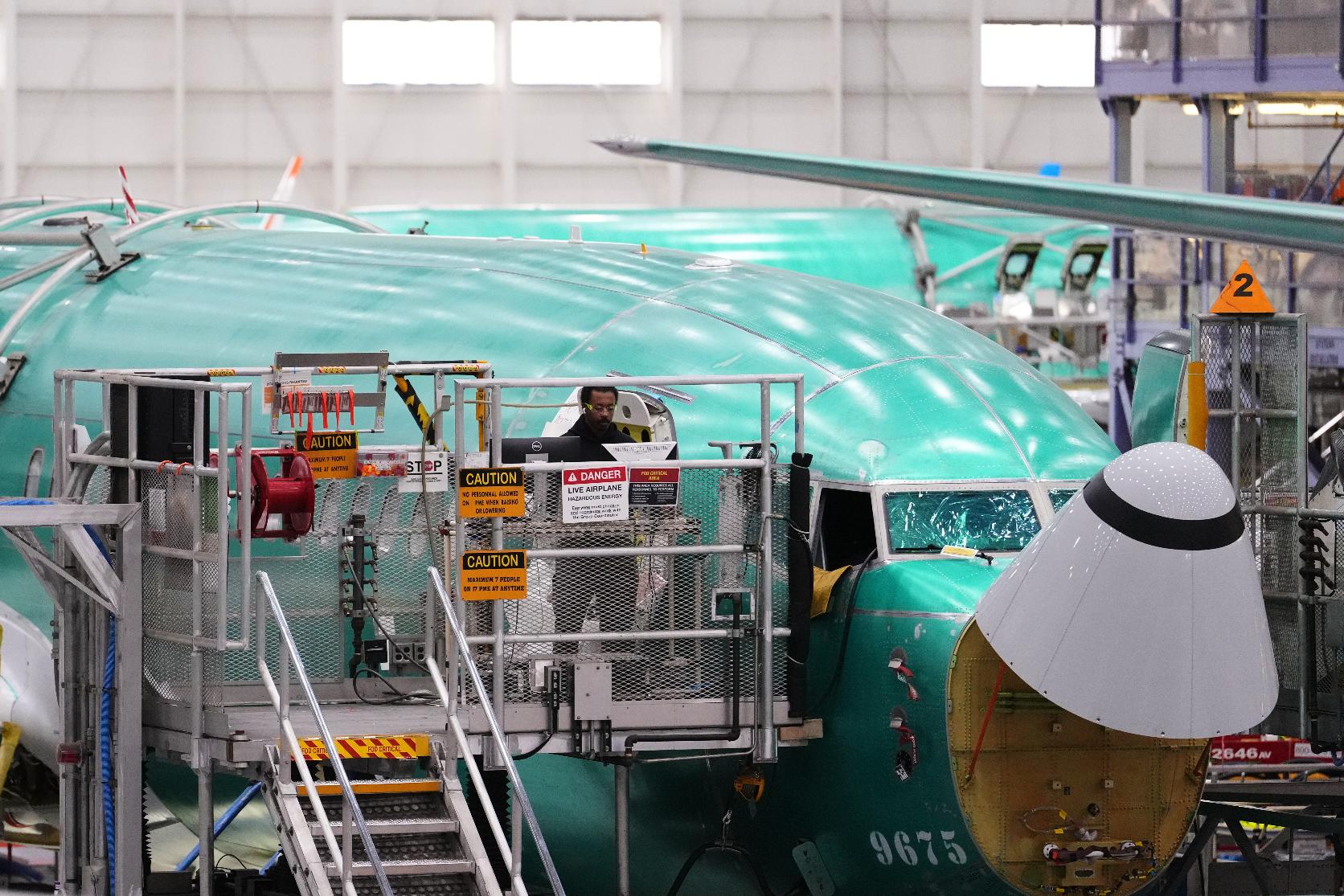 An employee works on a computer next to a Boeing 737 MAX airplane being built on the final assembly line during a media tour at Boeing's factory Wednesday, April 15, 2026, in Renton, Wash. (AP Photo/Lindsey Wasson)