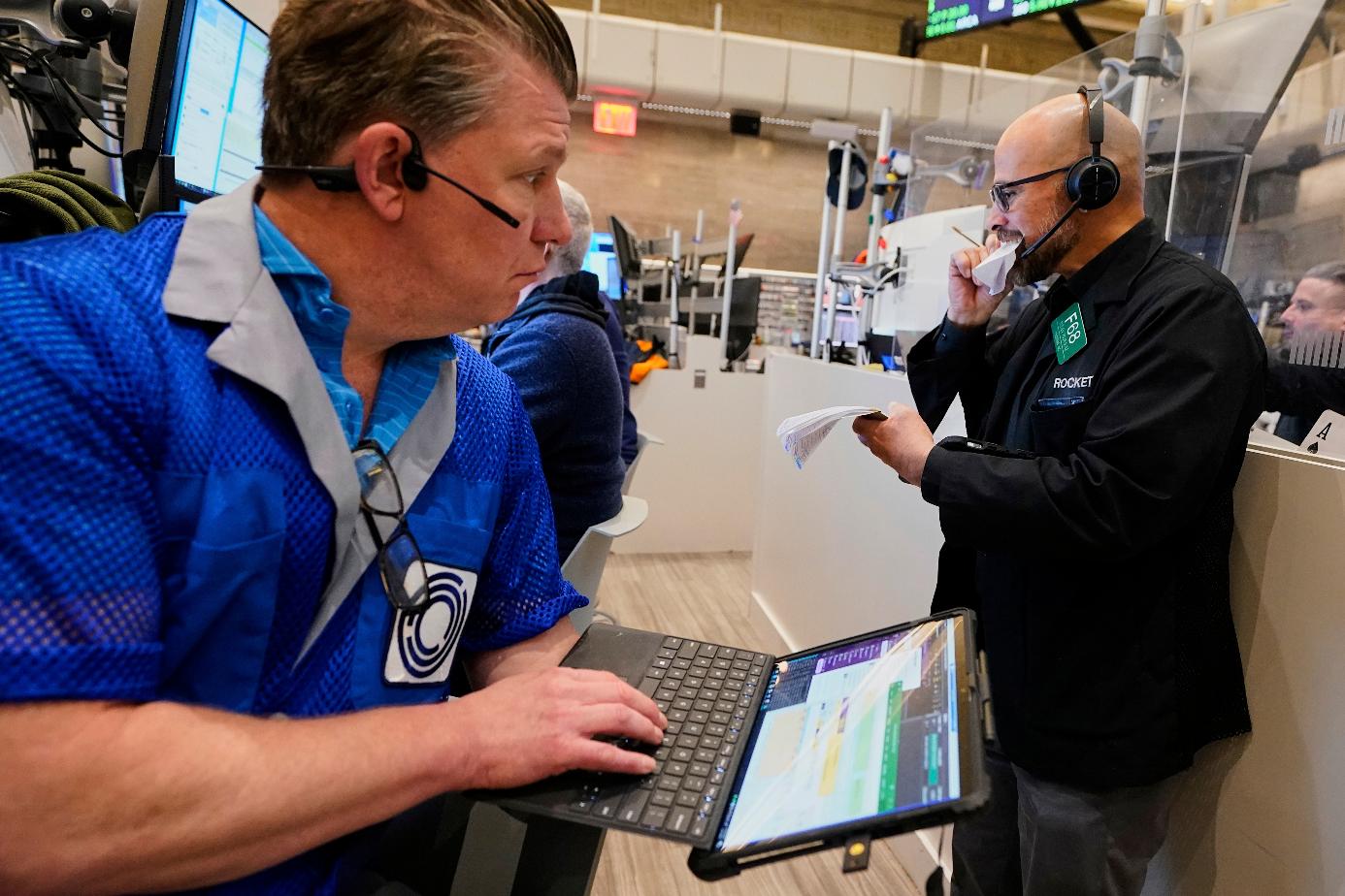 Options trader Steven Rodriguez, right, tears pages out of notepad as fellow trader Ed Nagle watches, on the floor of the New York Stock Exchange, Friday, April 11, 2025. (AP Photo/Richard Drew)
