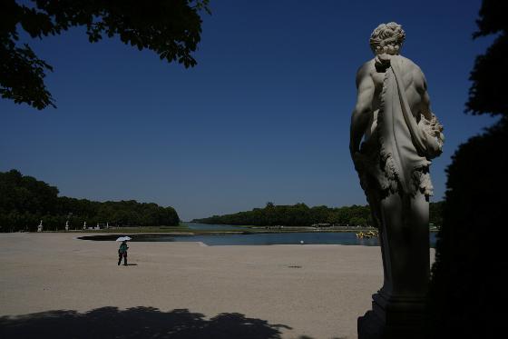 A woman shields herself from the sun with an umbrella as she walks in the garden of the Palace of Versailles, outside Paris, during a heat wave with temperatures soaring above 40 degrees Celsius (104 Fahrenheit), Monday, June 22, 2026. (AP Photo/Thibault Camus)