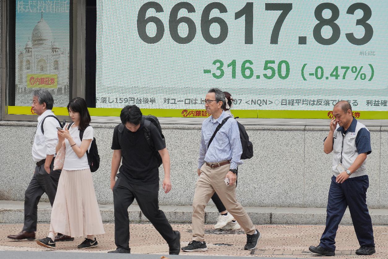 People walk in front of an electronic stock board showing Japan's Nikkei index at a securities firm Tuesday, June 2, 2026, in Tokyo. (AP Photo/Eugene Hoshiko)