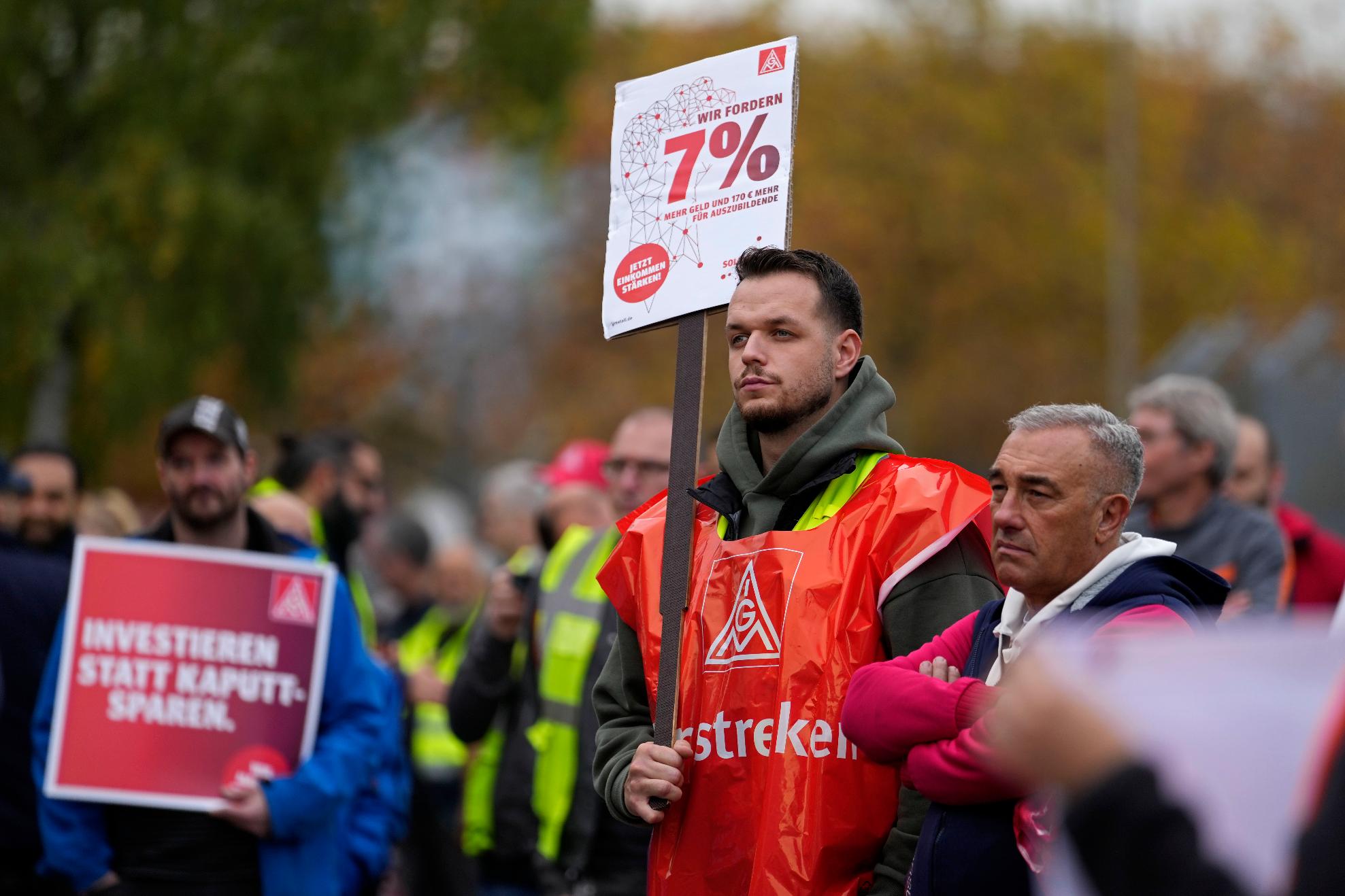 FILE -A worker holds a sign reading "investing instead of saving" during a nationwide warning strike of the union IG Metal at the car maker FORD factory in Cologne, Germany, Germany,, Oct. 29, 2024. (AP Photo/Martin Meissner, File)