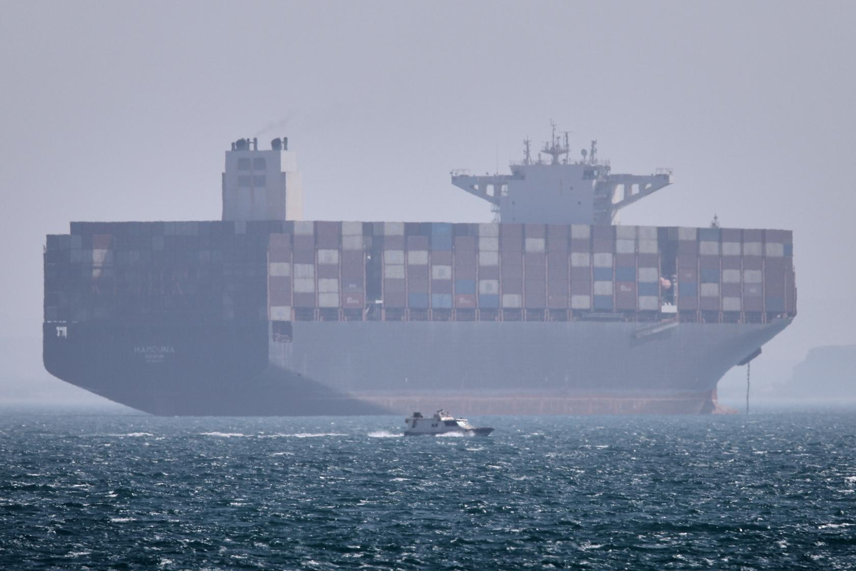 A container ship sits at anchor as a small motorboat passes in the foreground in the Strait of Hormuz off Bandar Abbas, Iran, Saturday, May 2, 2026. (Amirhosein Khorgooi/ISNA via AP)
