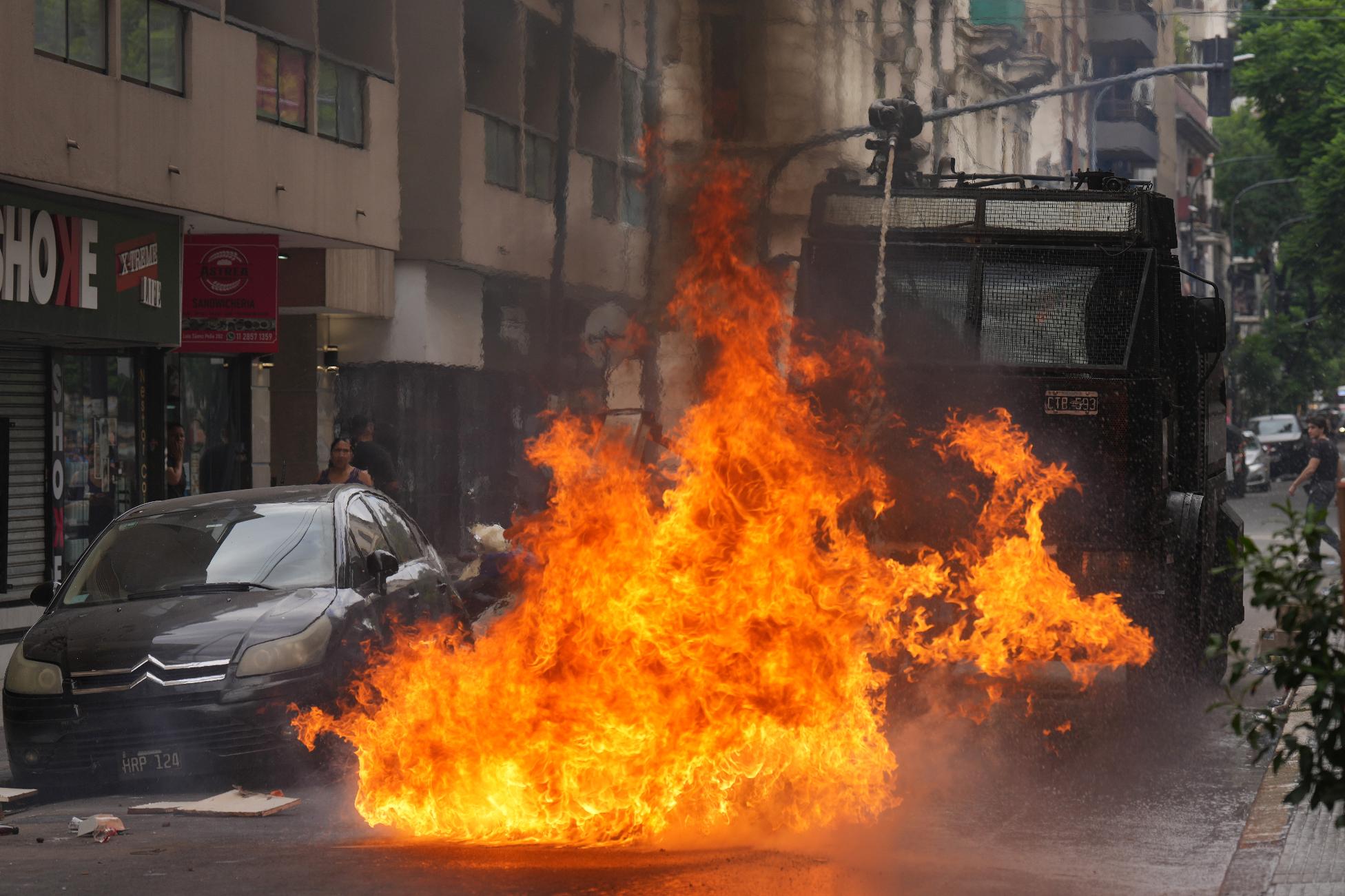 A police water cannon sprays a fire sparked by a Molotov cocktail during clashes at a march by trade unions and opposition groups against a labor reform bill proposed by President Javier Milei's government in Buenos Aires, Argentina, Wednesday, Feb. 11, 2026. (AP Photo/Gustavo Garello)