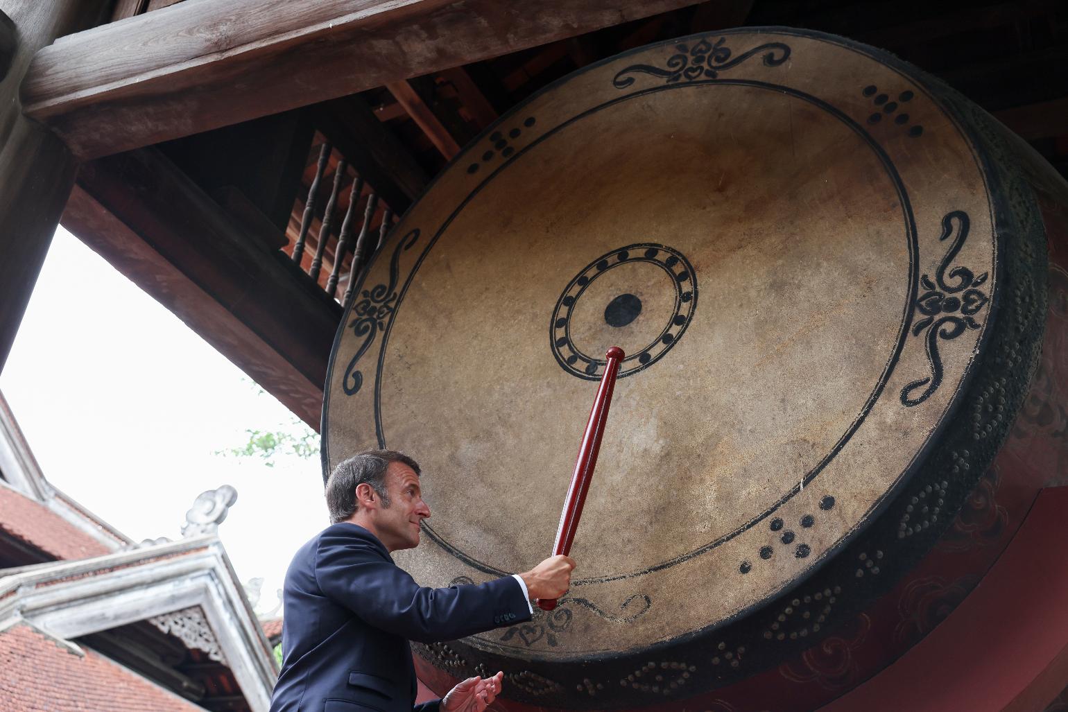 French President Emmanuel Macron beats a drum at Van Mieu temple during a luncheon with Vietnam's Communist Party General Secretary To Lam during Macron's first official trip to the country, in Hanoi, Vietnam, Monday, May 26, 2025. (Chalinee Thirasupa/Pool Photo via AP)