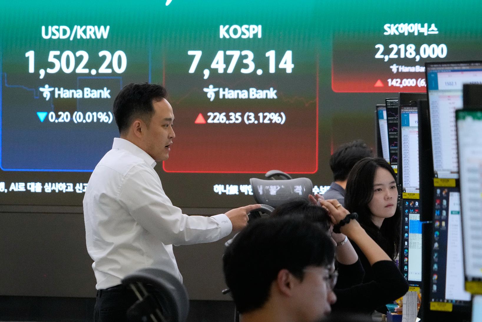 Currency traders work near a screen showing the Korea Composite Stock Price Index (KOSPI) and the foreign exchange rate between U.S. dollar and South Korean won at the foreign exchange dealing room of the Hana Bank headquarters in Seoul, South Korea, Thursday, July 9, 2026. (AP Photo/Ahn Young-joon)