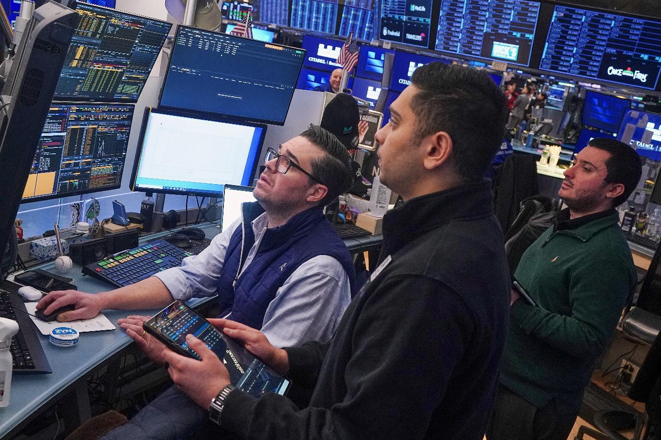 Traders Joseph Lawler, left, and Niall Pawa, center, and Drew Cohen work on the floor of the New York Stock Exchange, Thursday, Feb. 19, 2026. (AP Photo/Richard Drew)