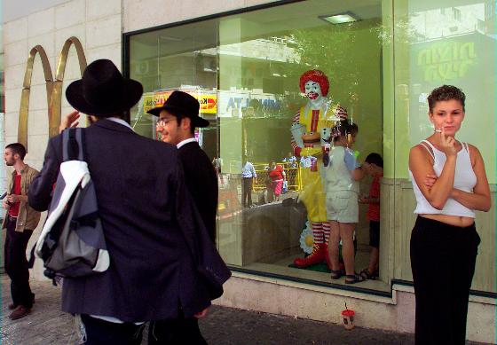 FILE - Residents of Jerusalem mingle inside and outside of the city's downtown McDonald's fast food restaurant Friday Aug. 16, 2002. McDonald’s is buying its restaurants in Israel from a longtime franchisee, hoping to reset sales that have slumped due to boycotts in the region. (AP Photo/David Guttenfelder, File)