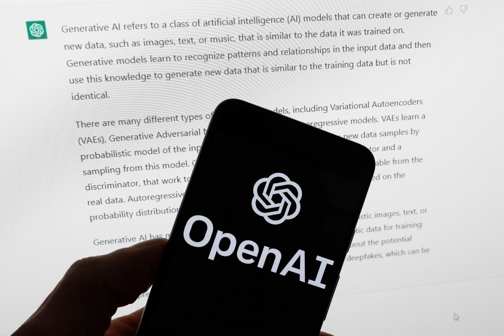FILE - The OpenAI logo is displayed on a mobile phone in front of a computer screen with output from ChatGPT, March 21, 2023, in Boston. (AP Photo/Michael Dwyer, File)