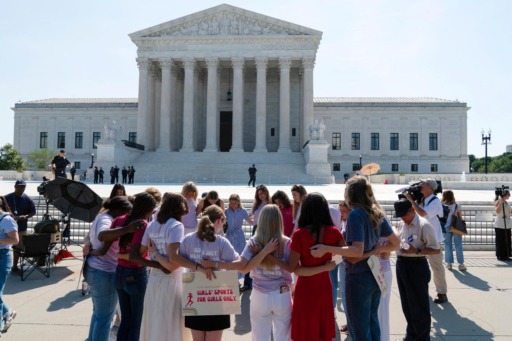 A group prays outside of the Supreme Court ahead of the court's ruling on whether transgender girls and women can play on school athletic teams, Tuesday, June 30, 2026, on Capitol Hill in Washington. (AP Photo/Jose Luis Magana)
