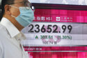 A man wearing a face mask walks past a bank's electronic board showing the Hong Kong share index in Hong Kong, Tuesday, Dec. 7, 2021. Asia stock markets followed Wall Street higher Tuesday as anxiety about the coronavirus's latest variant eased. (AP Photo/Kin Cheung)