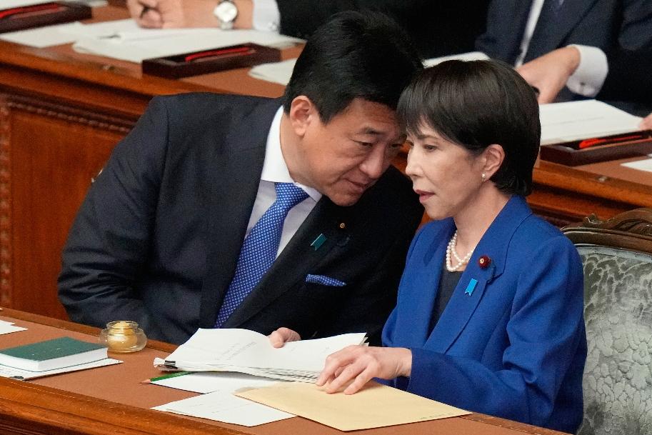 Japan's Chief Cabinet Secretary Minoru Kihara, left, speaks to Prime Minister Sanae Takaichi at the extraordinary session of parliament's lower house Friday, Oct. 24, 2025, in Tokyo. (AP Photo/Eugene Hoshiko)