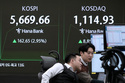 Currency traders watch monitors near a screen showing the Korea Composite Stock Price Index (KOSPI), left, at the foreign exchange dealing room of the Hana Bank headquarters, in Seoul, South Korea, Thursday, Feb. 19, 2026. (AP Photo/Ahn Young-joon)