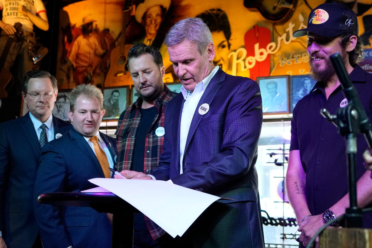 Gov. Bill signs a bill Thursday, March 21, 2024, in Nashville, Tenn. The legislation is designed to protect songwriters, performers and other music industry professionals against the potential dangers of artificial intelligence. Attending the ceremony are country music artists Luke Bryan, third form right, and Chris Janson, right. The signing took place in Robert's Western World, an historic honky tonk in downtown Nashville. (AP Photo/Mark Humphrey)