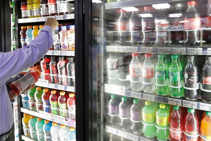 FILE - A shop owner reaches into a drink display refrigerator at his convenience store in Kent, Wash., Oct. 1, 2018. (AP Photo/Elaine Thompson, File)