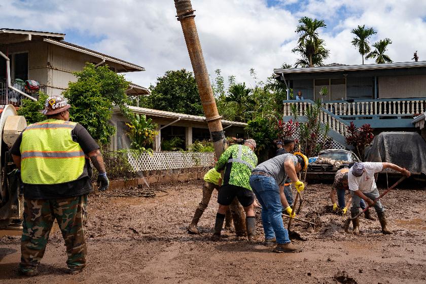 Volunteers assist in clearing mud using heavy equipment in a flooded residential neighborhood, Tuesday, March 24, 2026, in Waialua, Hawaii. (AP Photo/Mengshin Lin)