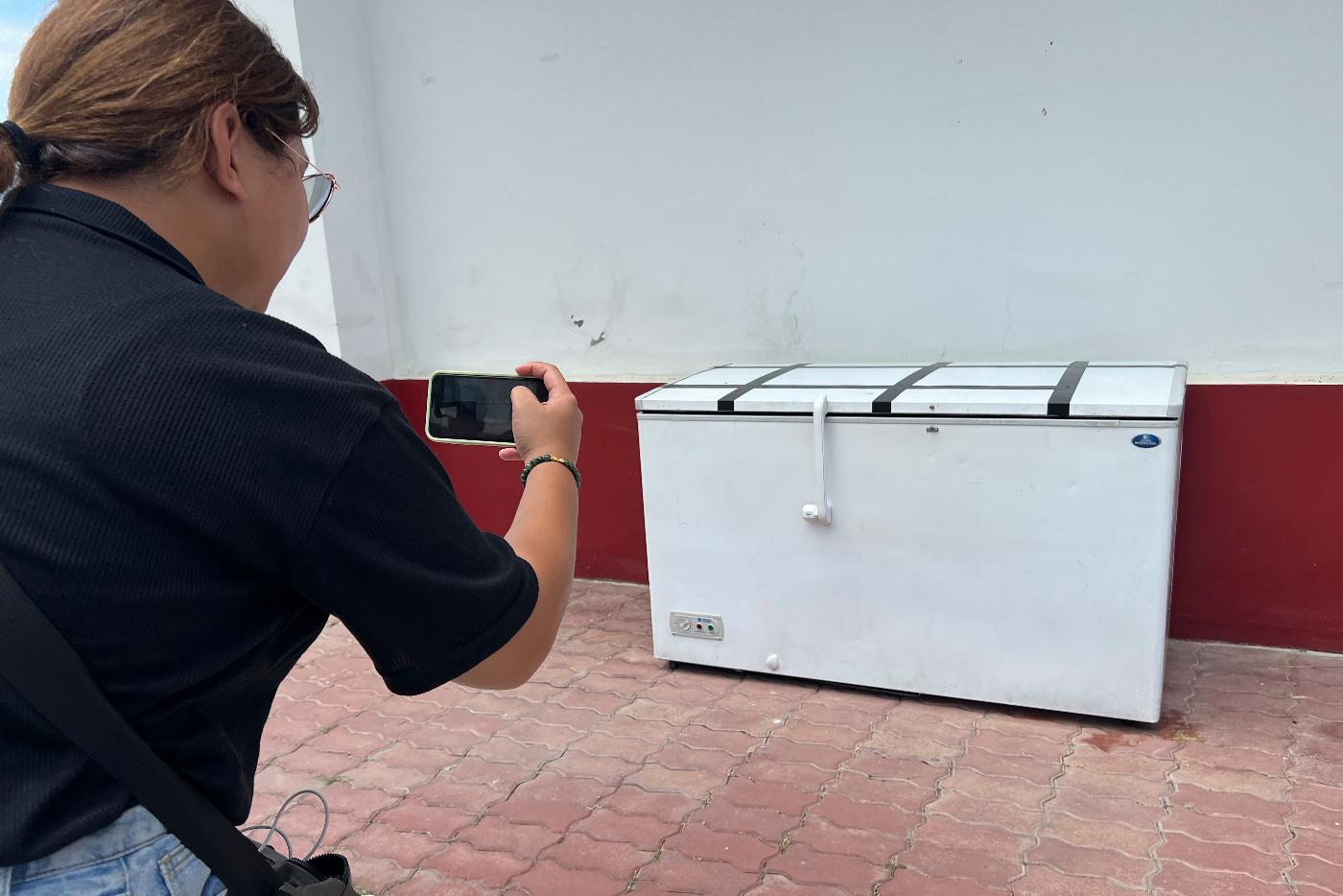A Thai reporter takes a photo of an empty freezer at the Nong Prue police station in Pattaya, Chonburi province, Thailand, Tuesday, July 11, 2023. The dismembered body of a 62-year-old German businessman Hans-Peter Mack who has been missing for a week has been found in the freezer of a house in southern Thailand, police said Tuesday. (AP Photo)