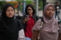A woman uses her mobile phone in Jakarta, Indonesia, Friday, March 6, 2026. (AP Photo/Dita Alangkara)