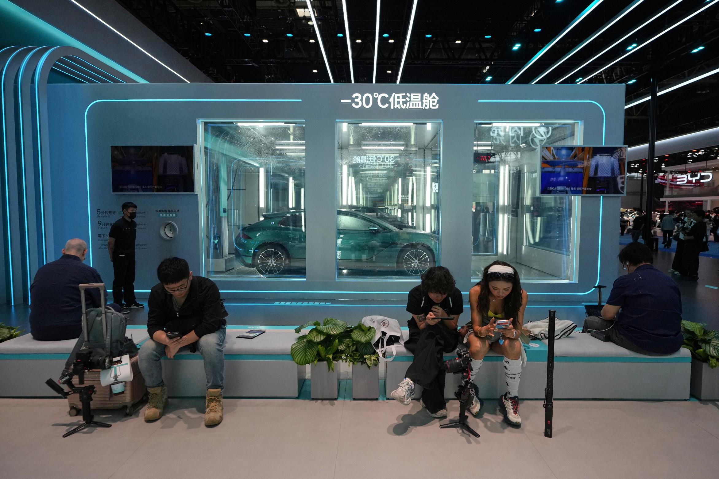Visitors take rest near a chamber with sub-zero temperatures that showcases the battery charging technologies from Chinese automaker BYD at the Auto China 2026, in Beijing, Saturday, April 25, 2026. (AP Photo/Andy Wong)