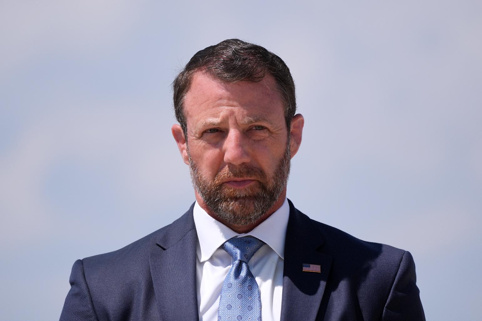 Homeland Security Secretary Markwayne Mullin, listens as President Donald Trump speaks to the press after returning and stepping off Air Force One, Wednesday, May 20, 2026, at Joint Base Andrews, Md. (AP Photo/Jacquelyn Martin)