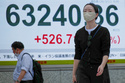 People walk in front of an electronic stock board showing Japan's Nikkei index at a securities firm Monday, May 11, 2026, in Tokyo. (AP Photo/Eugene Hoshiko)