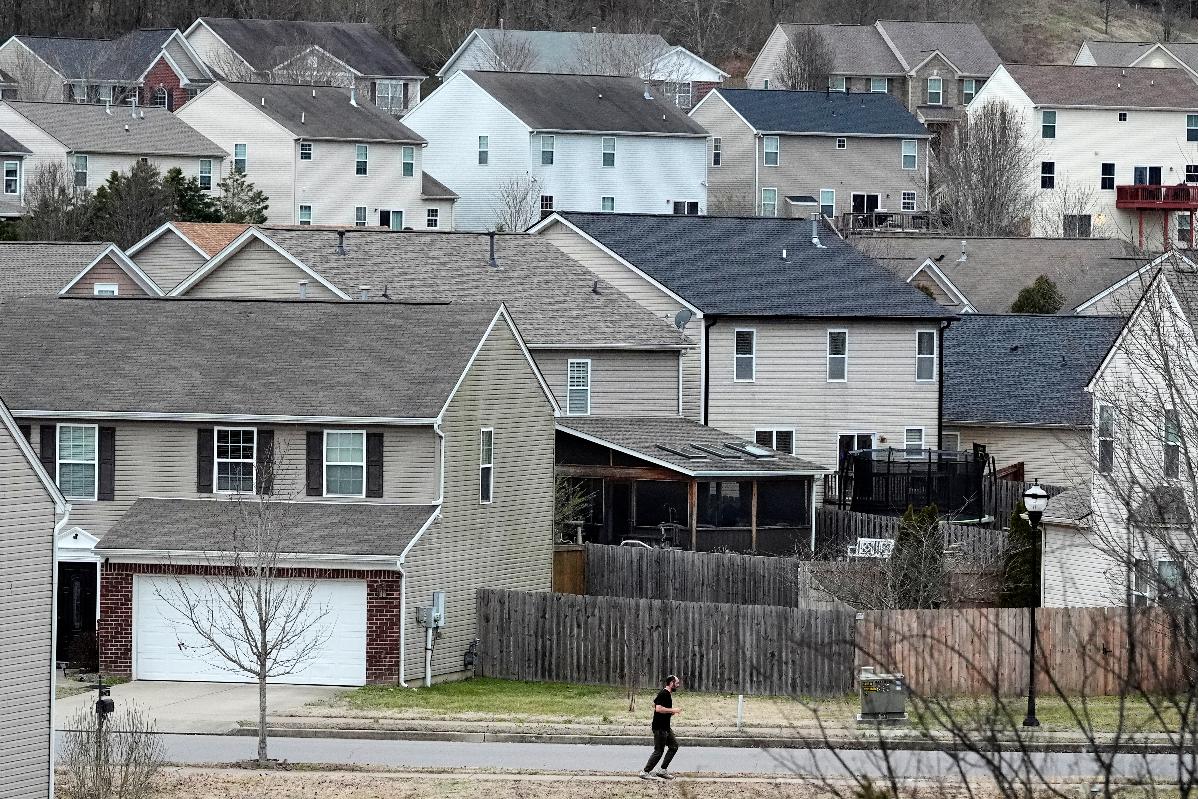 A person jogs past single family homes, Tuesday, Feb. 10, 2026, in Nashville, Tenn. (AP Photo/George Walker IV)