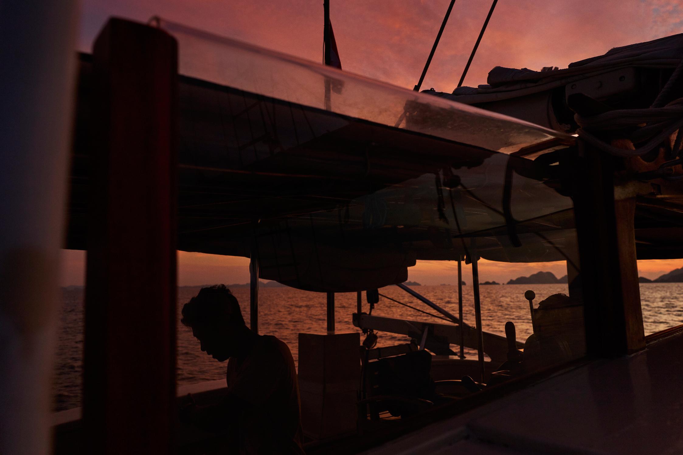 A crew member of the Raja Laut dive boat, is silhouette at sunrise aboard near Boo Windows diving site, Raja Ampat, Indonesia, Tuesday, March 3, 2026. (AP Photo/Claudia Rosel)