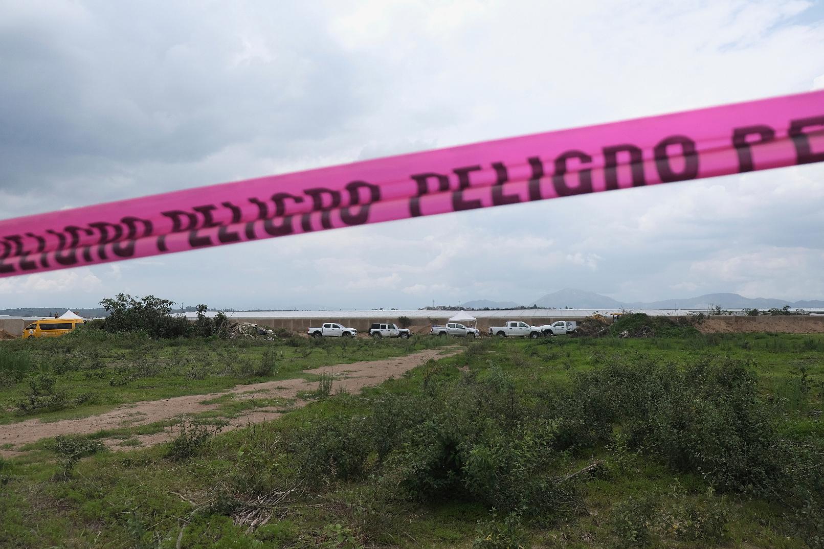 Danger warning tape streches along a Nextipac ranch where prosecutors say bodies were discovered in a mass grave during excavations for the construction, in the Zapopan municipality, Jalisco state, Mexico, Friday, July 11, 2025. (AP Photo/Alejandra Leyva)